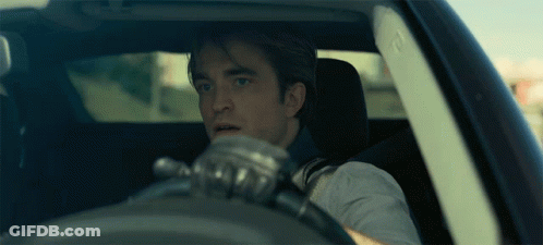A Man Wearing Gloves Is Driving A Car And Looking Out The Window GIF