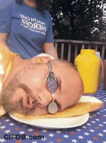 A Man Wearing Goggles Is Laying On A Plate With His Head On A Slice Of Pizza GIF