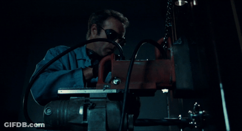 A Man Wearing Goggles Is Using A Machine In The Dark GIF