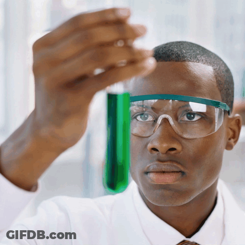 A Man Wearing Goggles Looks At A Green Liquid In A Beaker GIF