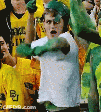 A Man Wearing Green Gloves And A White Shirt With The Letters Bu On It GIF
