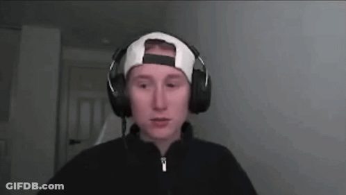 A Man Wearing Headphones And A Baseball Cap Is Looking At The Camera . GIF