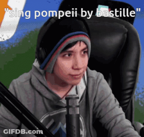 A Man Wearing Headphones And A Beanie Is Singing Pompeii By Bastille In Front Of A Microphone GIF