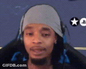 A Man Wearing Headphones And A Beanie Is Sitting In A Chair . GIF