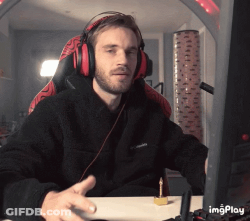 A Man Wearing Headphones And A Black Columbia Jacket Sitting At A Desk GIF