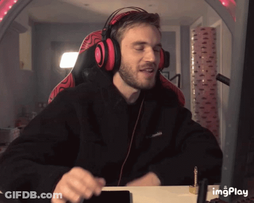 A Man Wearing Headphones And A Black Columbia Sweatshirt Is Sitting At A Desk GIF