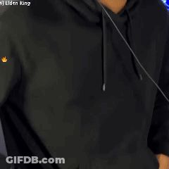 A Man Wearing Headphones And A Black Hoodie Is Standing In Front Of A Computer Screen . GIF