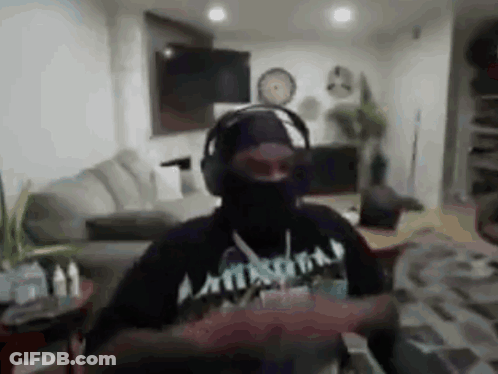 A Man Wearing Headphones And A Black Mask Is Dancing In A Living Room . GIF