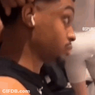 A Man Wearing Headphones And A Black Shirt Is Looking At The Camera . GIF