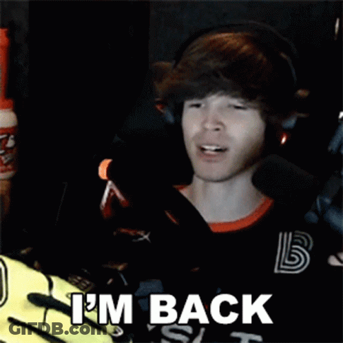 A Man Wearing Headphones And A Black Shirt Is Sitting In Front Of A Microphone And Saying I 'M Back . GIF