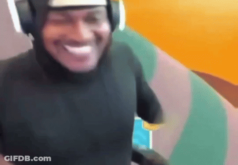 A Man Wearing Headphones And A Black Shirt Is Smiling And Looking At The Camera . GIF