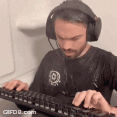 A Man Wearing Headphones And A Black Shirt Is Typing On A Keyboard . GIF