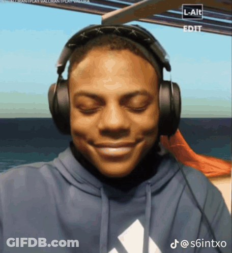 A Man Wearing Headphones And A Blue Adidas Sweatshirt Smiles GIF