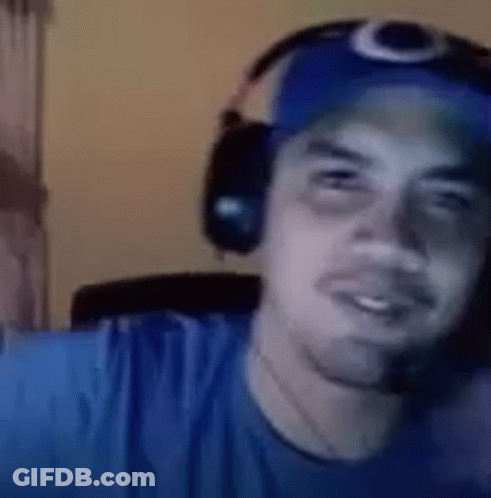 A Man Wearing Headphones And A Blue Hat Is Looking At The Camera . GIF
