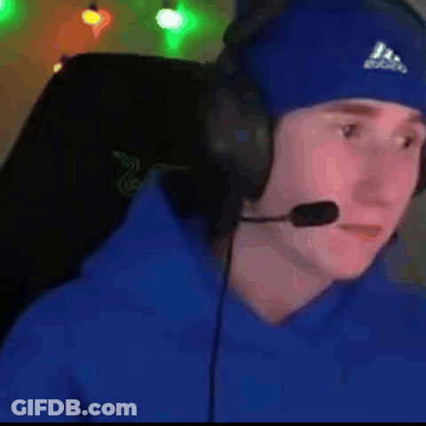 A Man Wearing Headphones And A Blue Hat Is Sitting In A Chair . GIF