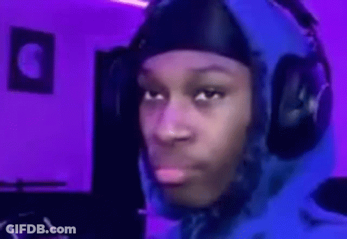 A Man Wearing Headphones And A Blue Hoodie Is Making A Funny Face In A Room With Purple Lights . GIF