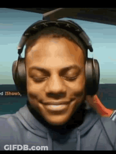 A Man Wearing Headphones And A Blue Hoodie Is Smiling . GIF