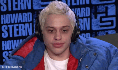 A Man Wearing Headphones And A Blue Jacket Is Sitting In Front Of A Sign That Says Howard Stern GIF