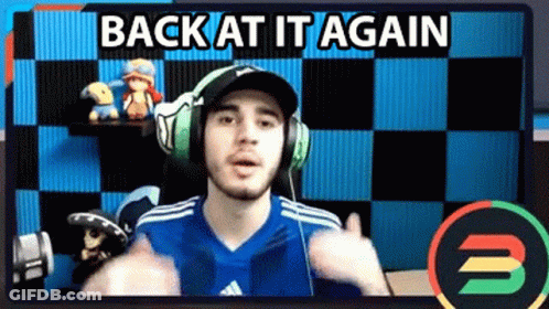 A Man Wearing Headphones And A Blue Shirt Is Giving A Thumbs Up In Front Of A Checkered Wall . GIF