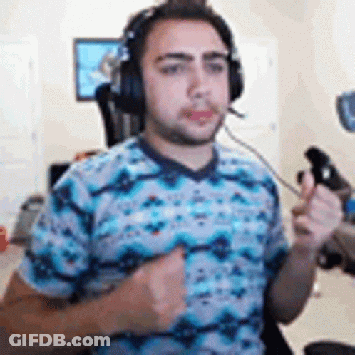 A Man Wearing Headphones And A Blue Shirt Is Holding A Controller In His Hand . GIF