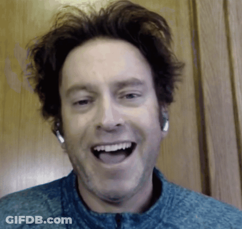 A Man Wearing Headphones And A Blue Shirt Is Smiling GIF
