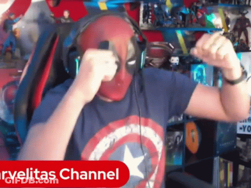 A Man Wearing Headphones And A Captain America Shirt Is Dancing In Front Of A Marvelitas Channel Sign GIF