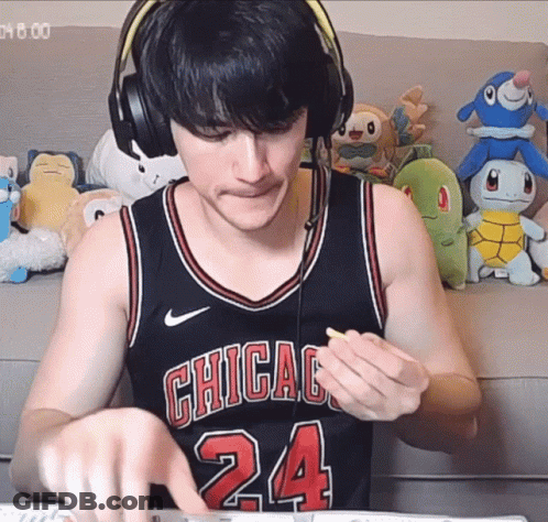 A Man Wearing Headphones And A Chicago 24 Jersey Eating A Snack GIF
