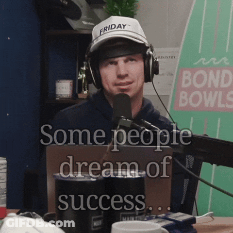 A Man Wearing Headphones And A Friday Hat Is Talking Into A Microphone GIF