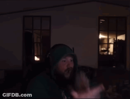 A Man Wearing Headphones And A Green Hoodie Stands In Front Of A Computer Screen GIF
