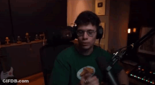 A Man Wearing Headphones And A Green Shirt Is Standing In Front Of A Microphone And Giving The Middle Finger . GIF
