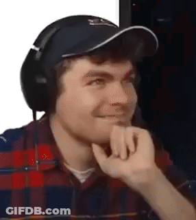 A Man Wearing Headphones And A Hat Is Making A Face . GIF