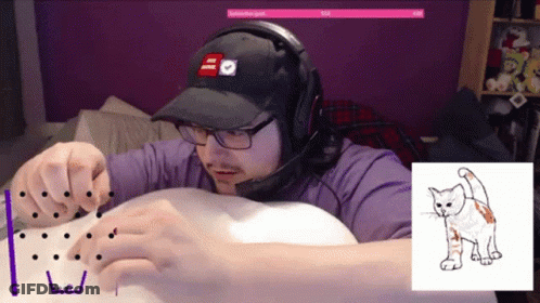 A Man Wearing Headphones And A Hat Is Playing A Game With A Picture Of A Cat Behind Him GIF