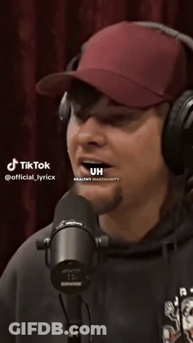 A Man Wearing Headphones And A Hat Is Singing Into A Microphone With Tiktok Written On The Bottom Of The Screen GIF