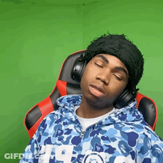 A Man Wearing Headphones And A Hat Is Sitting In A Chair . GIF