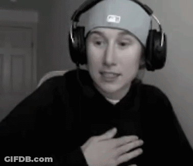 A Man Wearing Headphones And A Hat Is Sitting In Front Of A Computer . GIF