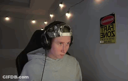 A Man Wearing Headphones And A Hat Is Sitting In Front Of A Computer . GIF