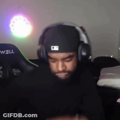 A Man Wearing Headphones And A Hat Is Sitting In Front Of A Well Gaming Chair . GIF