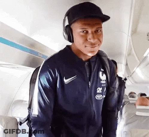 A Man Wearing Headphones And A Hat Is Walking On An Airplane . GIF