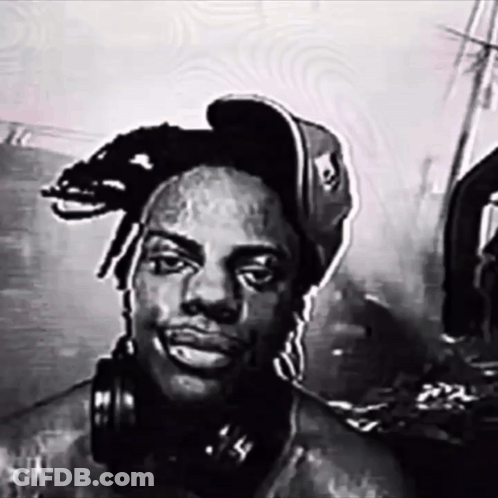 A Man Wearing Headphones And A Hat With A Skull On It GIF