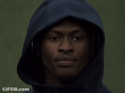 A Man Wearing Headphones And A Hooded Jacket Looks At The Camera GIF