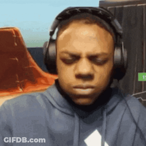 A Man Wearing Headphones And A Hoodie Is Making A Face . GIF