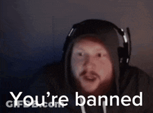 A Man Wearing Headphones And A Hoodie Is Saying You 'Re Banned . GIF