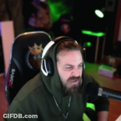 A Man Wearing Headphones And A Hoodie Is Sitting In Front Of A Microphone In A Gaming Chair GIF