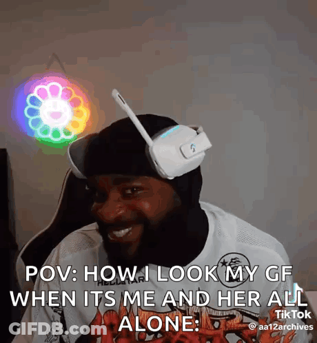A Man Wearing Headphones And A Mask Is Sitting In Front Of A Colorful Light . GIF