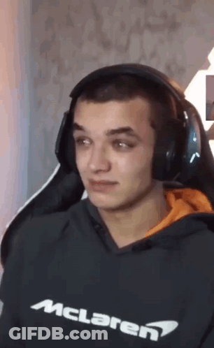 A Man Wearing Headphones And A Mclaren Sweatshirt Is Sitting In A Chair . GIF