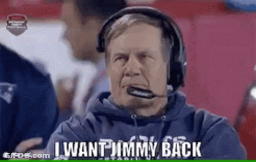 A Man Wearing Headphones And A Microphone Is Sitting On A Football Field . GIF