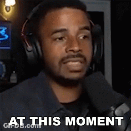 A Man Wearing Headphones And A Microphone Is Talking Into A Microphone And Saying `` At This Moment '' . GIF