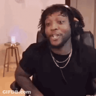 A Man Wearing Headphones And A Necklace Is Sitting In A Chair Making A Funny Face . GIF