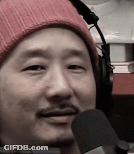 A Man Wearing Headphones And A Pink Beanie Looks At The Camera GIF