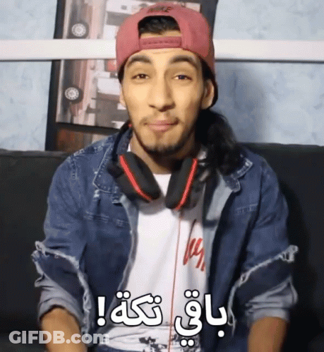 A Man Wearing Headphones And A Pink Nike Hat Is Sitting On A Couch And Making A Funny Face GIF